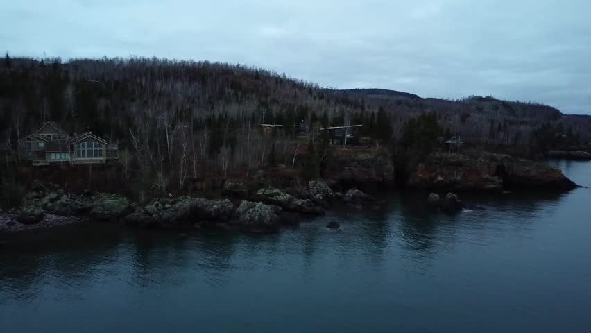 Aerial video takes a view of cabins on rocky cliffs near calm lake in Minnesota