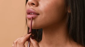 A young African American woman focuses on applying lip liner to enhance her lips. She appears confident and stylish, showcasing a healthy and athletic lifestyle. - Powered by Shutterstock - Get 15% off with code: PIKWIZARD15