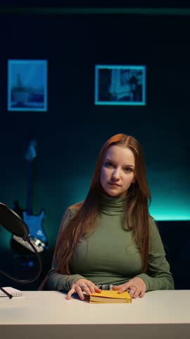 Vertical video Young girl films video review of book, browsing through pages, presenting synopsis to audience. Online star sponsored by publisher to show new novel release to readers, camera B