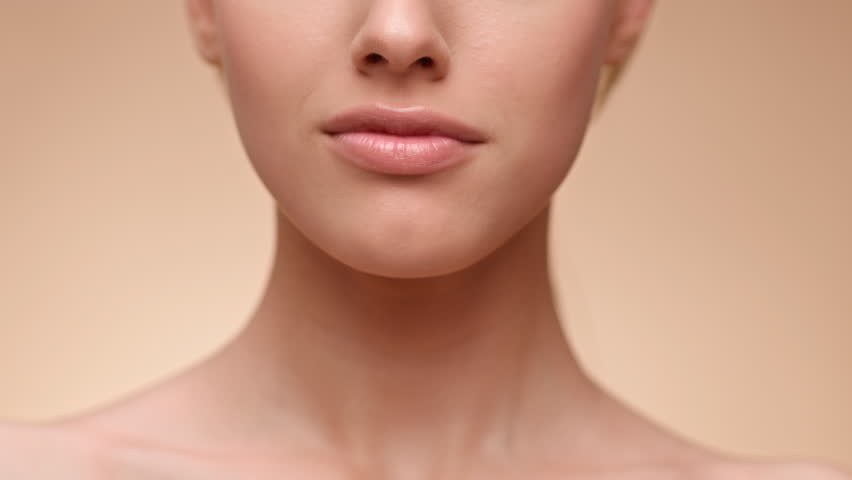 A young woman with a warm smile stands against a neutral background, highlighting her radiant natural beauty. The soft lighting enhances her features, creating a serene and inviting atmosphere.