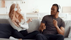 A biracial couple shares laughter and dance while listening to music in their cozy living room. The warm atmosphere reflects their love and deep connection as they bond happily. - Powered by Shutterstock - Get 15% off with code: PIKWIZARD15
