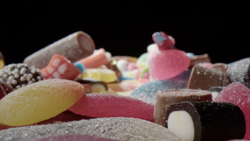 Probe slider shot over assortment of sugary colorful candy, sweet tooth concept