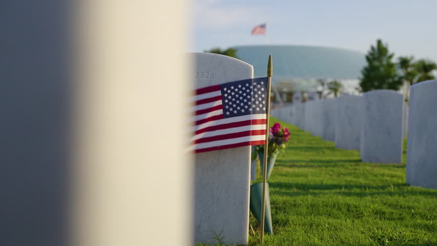 Army veteran cemetery white headstones decorated with flowers and USA flags. Tombs of retired military soldiers. Memorial Day concept.