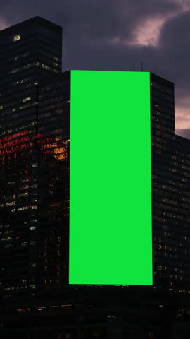 A large billboard with a green screen for advertising on the building wall.