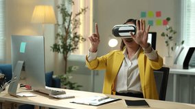 Young businesswoman wearing vr headset is sitting at desk in modern office and interacting with virtual reality, exploring immersive digital world - Powered by Shutterstock - Get 15% off with code: PIKWIZARD15