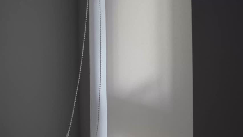 A man opens roller blinds, installing and operating windows in a house 