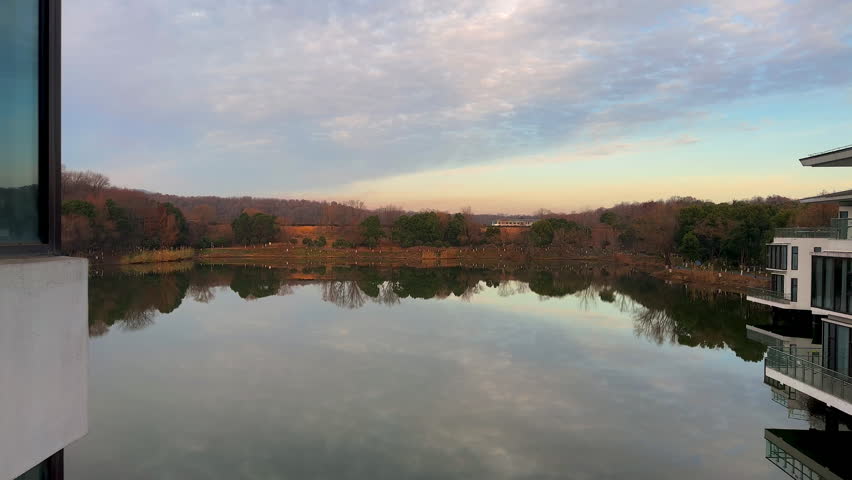 Time lapse of reflections of the peaceful pond at sunrise in winter Zijin or Purple Palace State Guesthouse, Nanjing, Jiangsu, China.