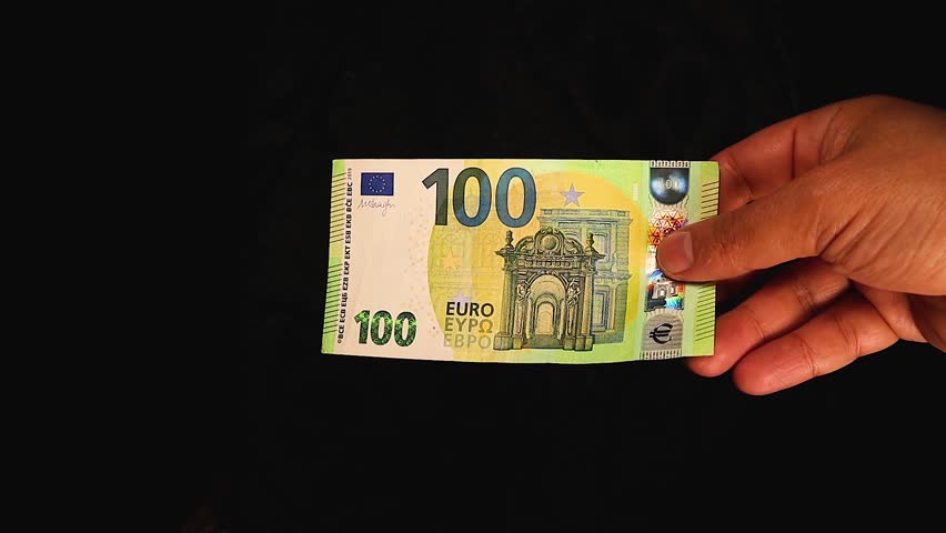 Hand holding a €100 euro banknote passes it to another hand in a smooth transaction. A symbol of European currency, financial exchange, or trade in a professional and clean setting.