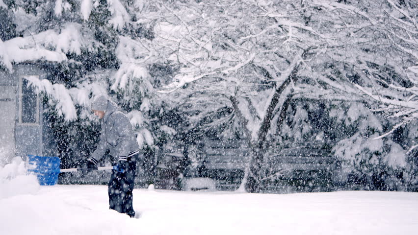 Senior Woman Shoveling Snow During Heavy Winter Storm in Slow Motion. Peaceful Scene of Elderly Person Clearing Snowy Backyard