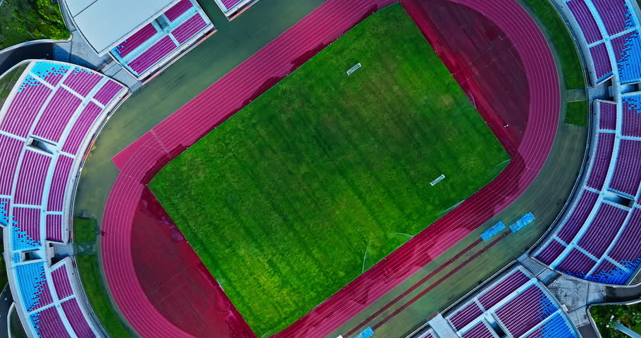 Aerial view of a stadium with green grass and running track. Top view.