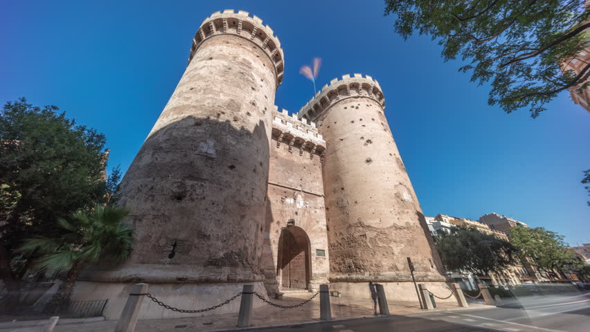 Towers of Quart timelapse hyperlapse in Valencia, Spain. Historical medieval gate, part of the ancient city walls. Popular landmark with a rich cultural heritage. Blue sky and street traffic scene.
