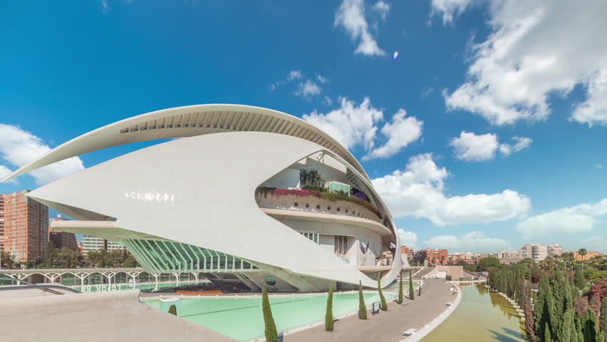 Aerial timelapse hyperlapse of the Palau de les Arts Reina Sofia in Valencia during sunny day. Iconic opera house by Calatrava featuring futuristic curves and reflecting pools under cloudy sky. Spain.