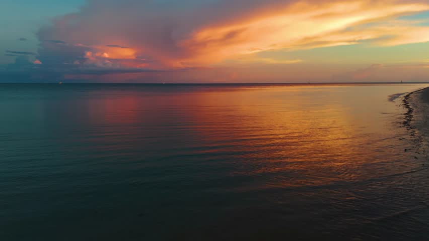 Footage of a beautiful orange and cloudy sunset over the Indian Ocean in Madagascar, capturing the stunning view of the horizon with dramatic skies and vibrant colors.
