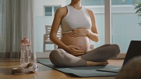 Pregnant woman practicing yoga or Pilates at home, following a lesson on her computer, relaxing and finding balance as she embraces self-care and mindfulness during pregnancy - Powered by Shutterstock - Get 15% off with code: PIKWIZARD15