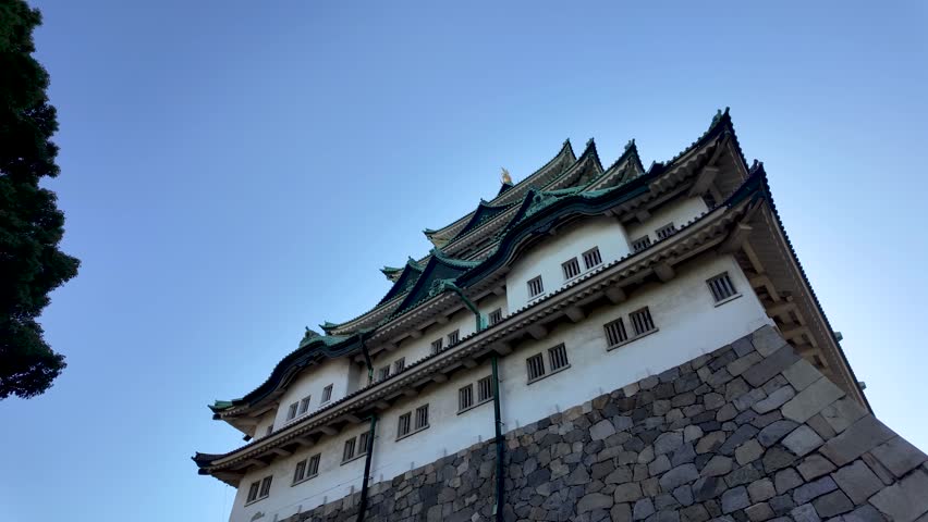 Nagoya , Japan - 11 07 2024: Looking Up at the Magnificent Nagoya Castle Under Clear Blue Skies. Panning Shot