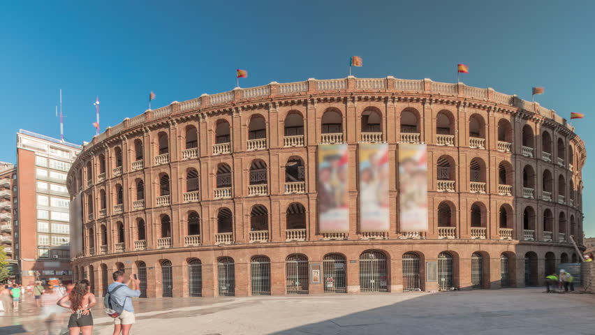 Panorama showing Bullring of Valencia (Plaza de Bous) timelapse and Bullfighting Museum, near Nord station. People walking around the historic amphitheater with a blue sky backdrop. Valencia, Spain.