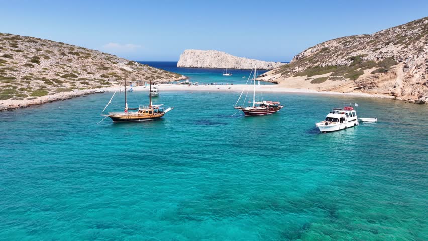 Aerial drone cinematic video of tropical paradise exotic island bay with emerald crystal clear two sided beach visited by luxury yachts and sail boats in Caribbean destination