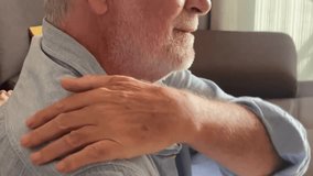 Senior man sitting on a couch at home, massaging his back and shoulder while feeling fatigued, stressed, and dealing with age-related pain, discomfort, arthritis, and other physical issues due aging - Powered by Shutterstock - Get 15% off with code: PIKWIZARD15