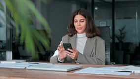 Middle aged Hispanic business manager ceo using cell phone mobile app, laptop. Smiling Latin or Indian mature woman businesswoman holding smartphone sit in office working online on gadget, copy space. - Powered by Shutterstock - Get 15% off with code: PIKWIZARD15