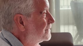 Side profile of a senior man seated indoors at home, smiling subtly with a calm and peaceful demeanor. Gentle lighting highlights the introspective and serene mood of the domestic environment - Powered by Shutterstock - Get 15% off with code: PIKWIZARD15