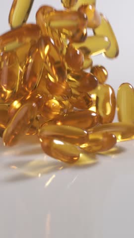 Vitamins and supplements fall onto a table in slow motion. Vertical Video.