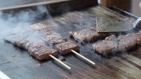 Chef grilling skewered Japan Wagyu beef or meat with a fire blowtorch. Close up of delicious grilled on the meat by grill pan and blow torch. Street food preparation with vibrant hot flames in Japan - Powered by Shutterstock - Get 15% off with code: PIKWIZARD15