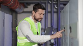 Bearded man in uniform with laptop in boiler room. Engineer or plumber inspects heating system equipment and pipes. - Powered by Shutterstock - Get 15% off with code: PIKWIZARD15