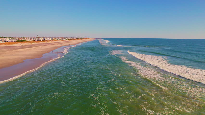 A drone footage of a wooden pier on a sandy beach on a sunny day in Avalon city, New Jersey, USA
