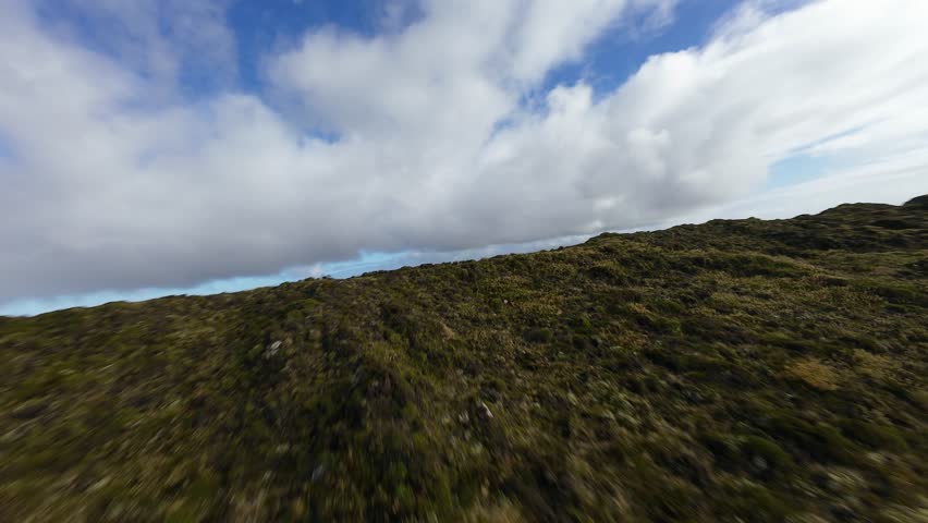 Mountain crater lake, hiking path leading up to the lake. Green lush mountain surroundings. FPV drone flight