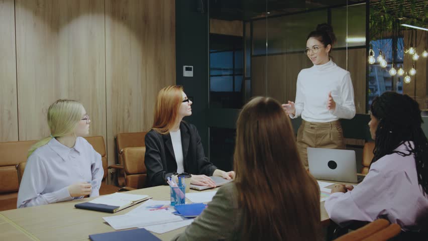 In a modern office, a group of professional women engages in a collaborative discussion, showcasing exceptional teamwork and strong communication skills in a business setting