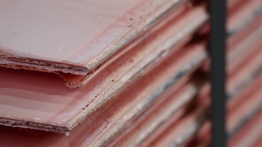 A panning close-up shot of sheets of copper cathodes stacked on top of each other.