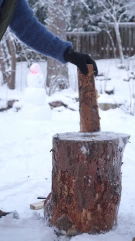 A middle-aged man is chopping firewood in the backyard of his house winter in Finland