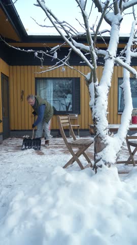 A middle-aged man is cleaning snow in the backyard of his house winter in Finland