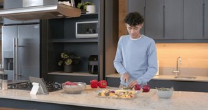Preparing vegetables, young man chopping ingredients in modern kitchen at home. Cooking, culinary, domestic, lifestyle, meal preparation, food - Powered by Shutterstock - Get 15% off with code: PIKWIZARD15
