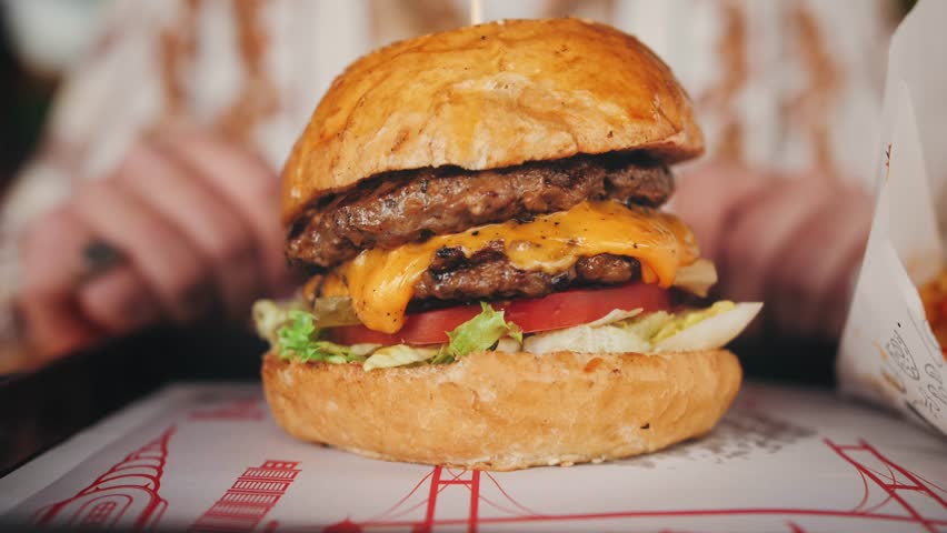Juicy freshly cooked cheeseburger close-up, hungry man picks up the burger. High quality 4k footage
