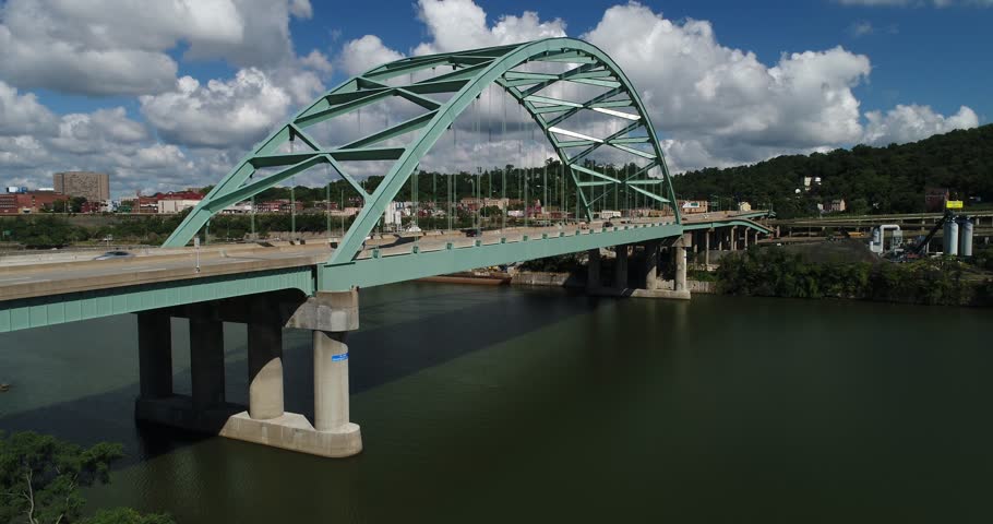 A daytime rising aerial establishing shot of traffic passing over the Birmingham Bridge over the Monongahela River near Pittsburgh, PA.  	