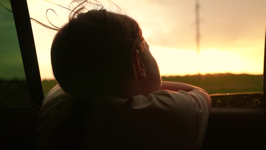 Happy family travels by car. Little girl kid enjoys family trip by car. Girl child looks out of car window. Child holiday. Family vacation. Girl kid looking out car window. Child girl look out window