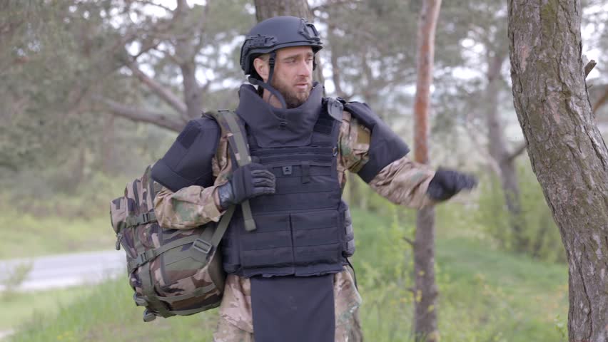 Young soldier in uniforms and tactical vest works in the forest and prepares for action at a temporary forest base. A man does in the work of demining the territory