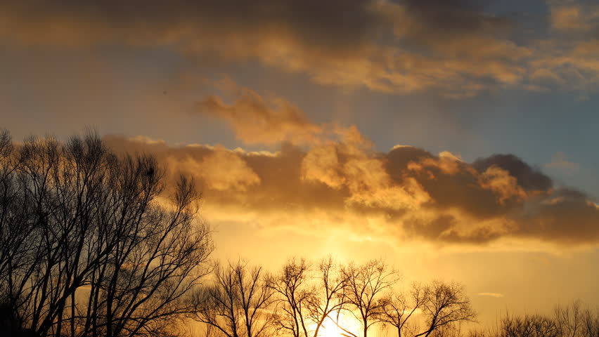Beautiful golden sunset with cumulus clouds floating across the sky. Orange evening, golden hour, cloudy sky. 4K video