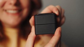 Attractive european adult woman holding small jewelry box with proposal diamond ring on grey wall background. Lady smiling, she is happy to get present, proposition for marriage.  - Powered by Shutterstock - Get 15% off with code: PIKWIZARD15
