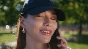 Closeup woman talking mobile phone in beautiful summer park. Portrait of relaxed female student in cap speaking cellphone in sunny street. Carefree girl enjoy smartphone call in urban green garden - Powered by Shutterstock - Get 15% off with code: PIKWIZARD15