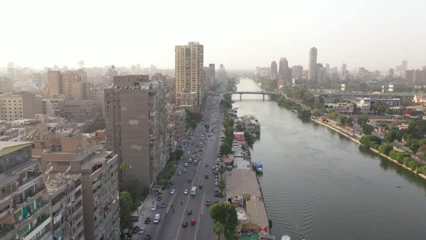 Aerial of the Nile River meanders through Cairo city, with a drone gliding past the beauty of Cairo, Egypt, embodying the concept of urban vitality and architectural marvels
