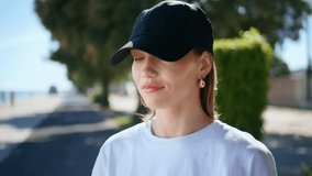 Relaxed woman wearing earphones on sunny urban street closeup. Serene lady enjoying music in wireless earbuds calm summer day outdoors. Portrait smiling brunette in cap closing eyes listening sound. - Powered by Shutterstock - Get 15% off with code: PIKWIZARD15