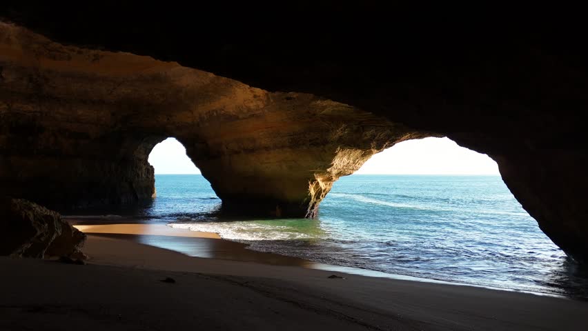 Inside Benagil Cave. Straight line drone shot. Boat passing entrance.