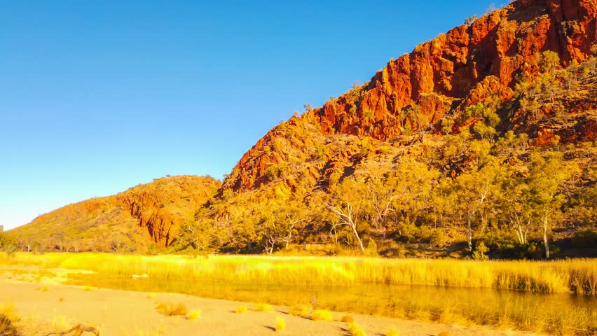 TIME LAPSE: sunset panorama of Glen Helen Gorge with permanent waterhole on Finke River. Tjoritja - West MacDonnell Ranges in Northern Territory, Central Australia. Australian outback Red Centre Way.