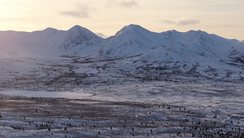 A cinematic aerial shot showcasing snow-covered mountains and the pristine Fish Lake landscape near Whitehorse, Yukon, capturing the raw beauty of Canada