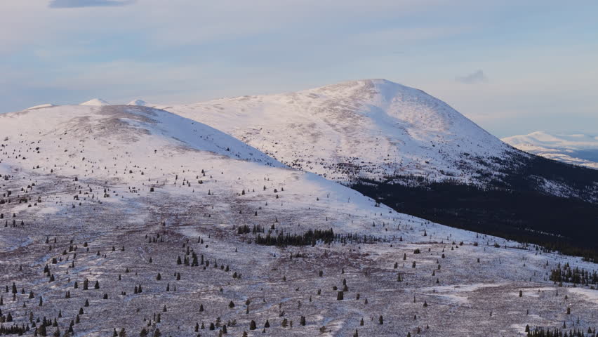 A cinematic smooth aerial shot of snow-capped mountains near Fish Lake, Whitehorse, Yukon, Canada, showcasing the incredible beauty of this remote wilderness and the stunning northern landscape.