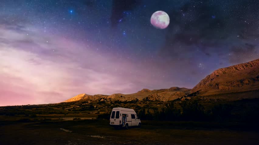 White camper van parked under a starry night sky with mountains in the background. Travel and adventure concept