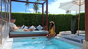 a couple enjoy a tranquil afternoon by a private pool. The sun shines brightly, enhancing their peaceful escape. Digital Nomad at work or freelancer with laptop in private pool villa - Powered by Shutterstock - Get 15% off with code: PIKWIZARD15