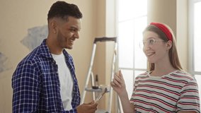 Couple painting together in their new home, sharing a playful moment with brushes in hand, captured in a bright living room setting emphasizing love and teamwork - Powered by Shutterstock - Get 15% off with code: PIKWIZARD15